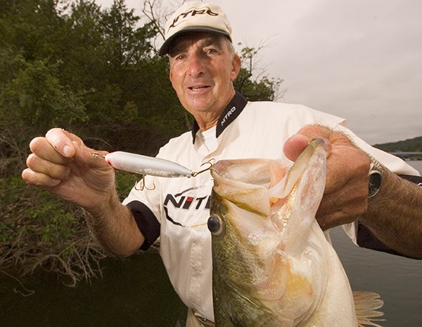 Charlie Campbell poses holding a bass fish