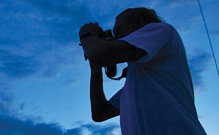 Silhouette of person looking through binoculars with dark blue background