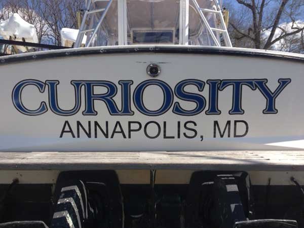 Rear (stern) of a white boat with the boats name in very large print and the city and state listed just below it