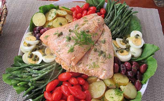 a plate of salmon salad greek style with potatoes tomatoes and hard boiled eggs