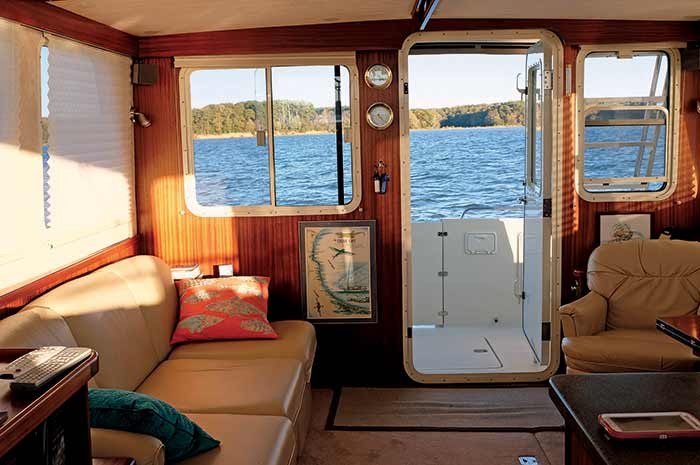 Cabin interior with couch, chair and coffe table with iPad on it looking out on the water