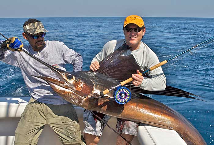 Two men holding a large fishing catch for a photo op before releasing it back into the water