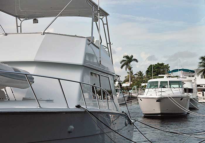 A line of large white powerboats tied up to a long dock