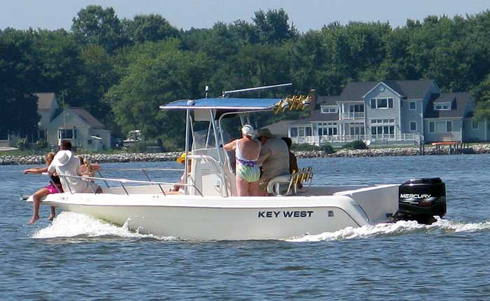 A small  KEY WEST powerboat is underway with 6 people aboard including several at the bow with their legs hanging over the side.