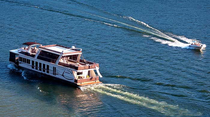 Houseboat cruising on Lake Cumberland with a smaller poerboat passing on the right