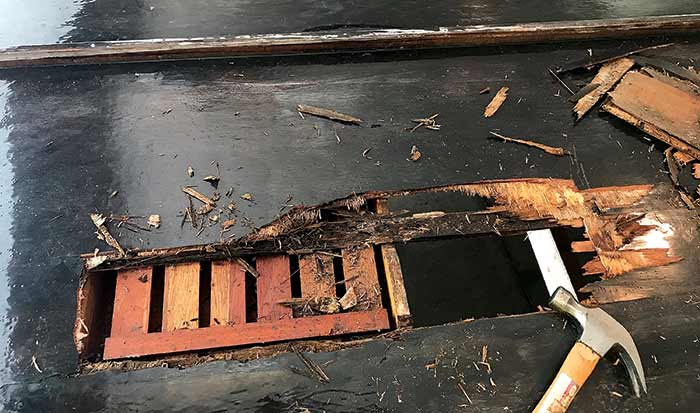 Hull of wooden runabout boat with large hole in it