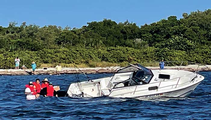Four people in orange life jackets waiting to be rescued from a sinking 19-foot boat in Tampa Bay
