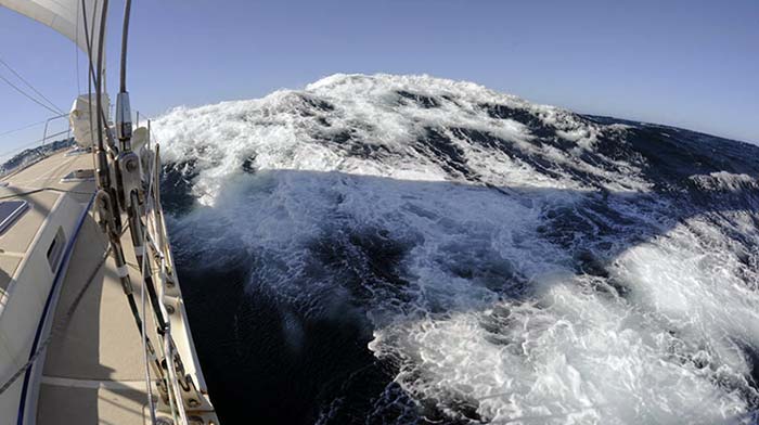 Sailboat cresting a large wave
