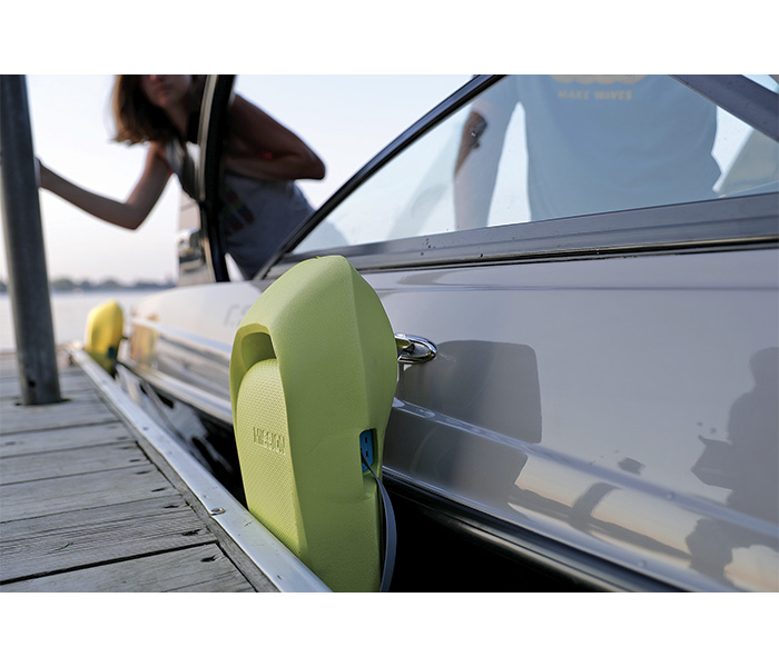 Close up photo of a boat using a yellow fender to protect from dock.
