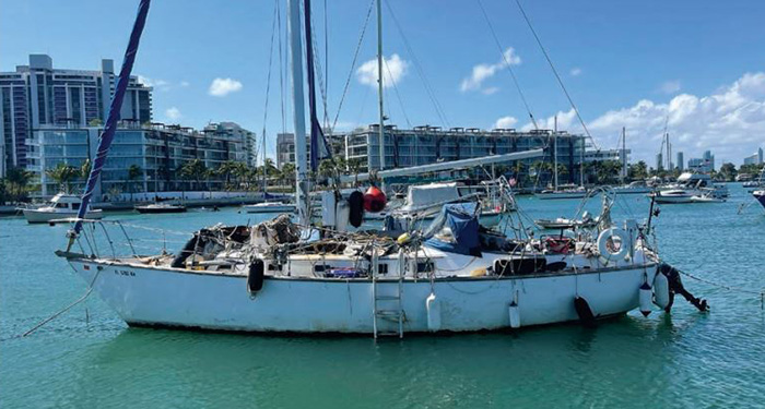 An abandoned white sailboat off the coast during a sunny day. 