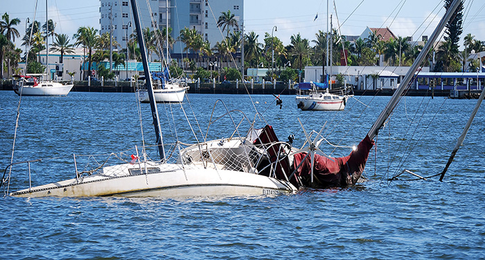 Two abandoned vessels half submerged in open waters on a sunny day.