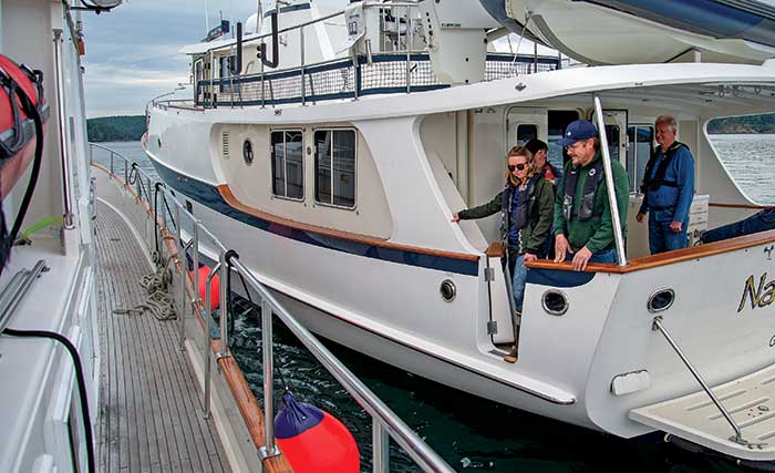 Two trawlers side-by-side, one with a group of people on it, in position for a boat-to-boat personnel transfer