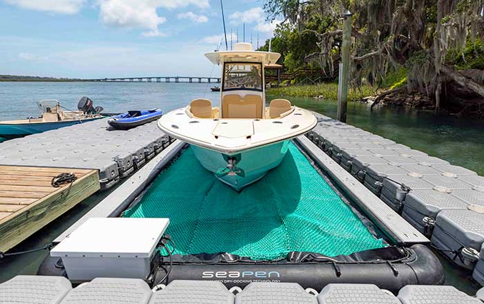 Front view of a turquoise and white powerboat atop a SeaPen floating dry dock system