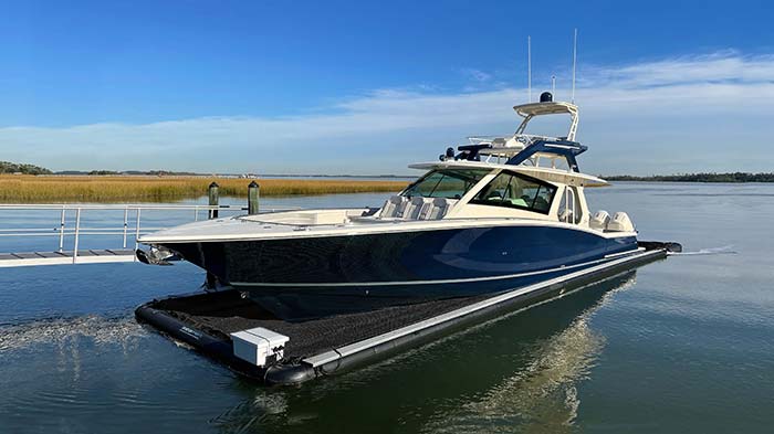 Large blue and white powerboat sitting atop a mesh Seapen floating dock on the water