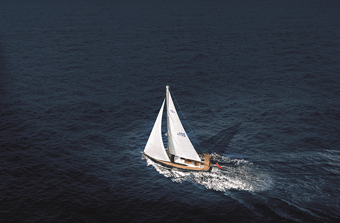 White sail boat out on the bright blue open waters during a sunny day.