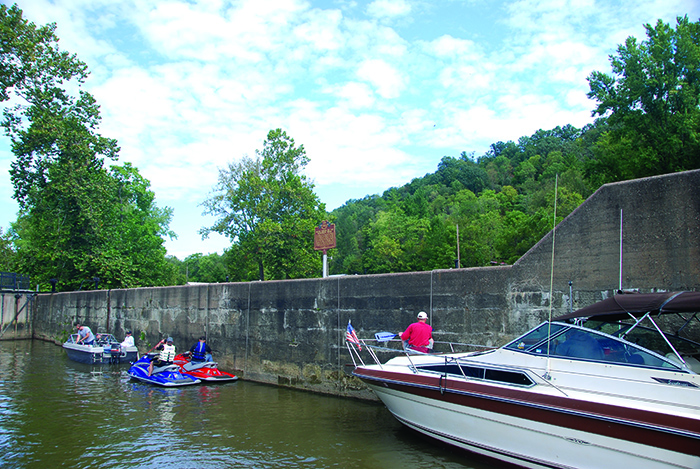 Two white boats and two sea doos near a retaining wall.