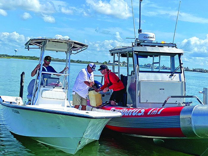 TowBoatU.S. assisting two adult males in a white boat on the open waters in the Gulf Coast on a sunny day.