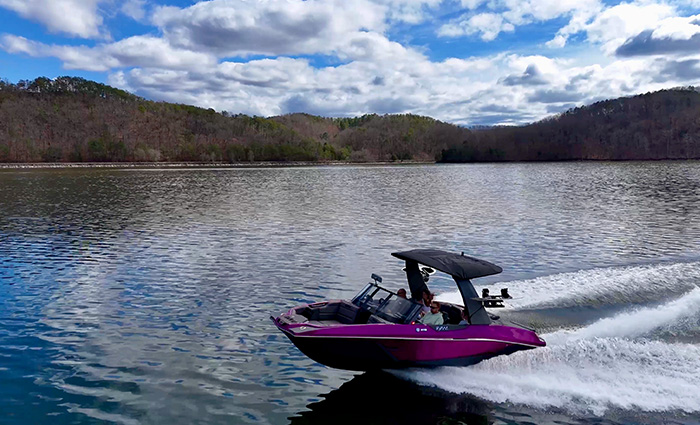 Pink and black vessel out on open waters during a cloudy day.
