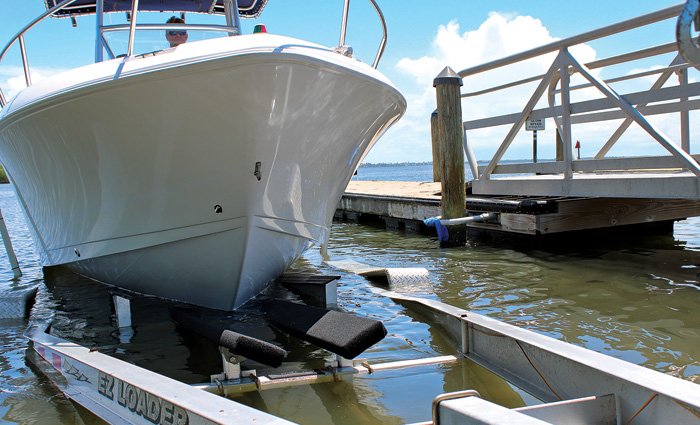 Adult male loading a white vessel to a trailer next to a wooden dock.