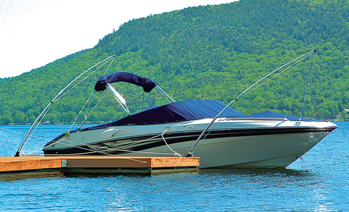 A navy and white vessel next to a wooden dock with clear blue skies and green hills in the background.