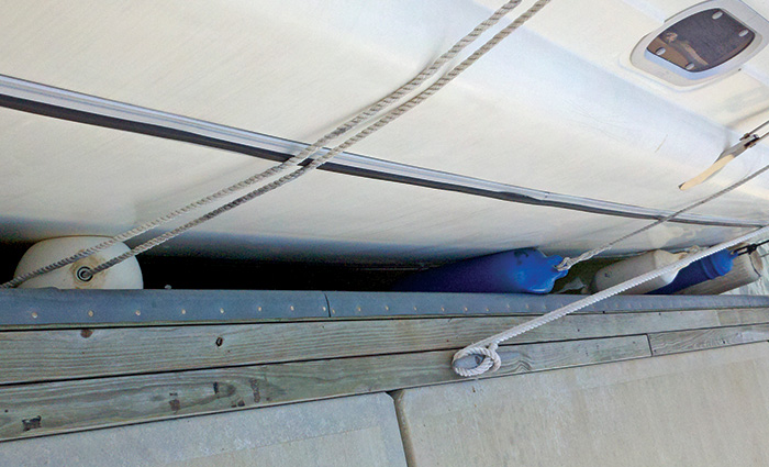 Undersized white and blue fenders providing little protection for a white vessel next to a dock.