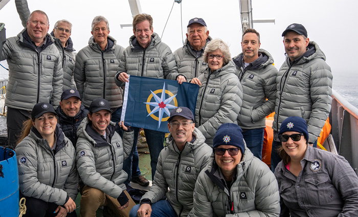 Group of adults wearing gray jackets posing for a photo.