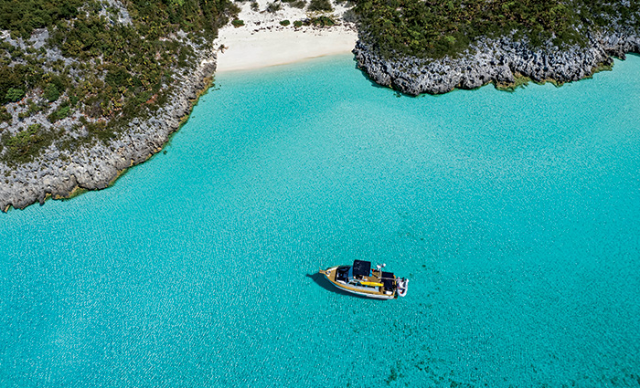 Aerial photo of a boat along the coast of the clear blue Bahama waters during a sunny day.