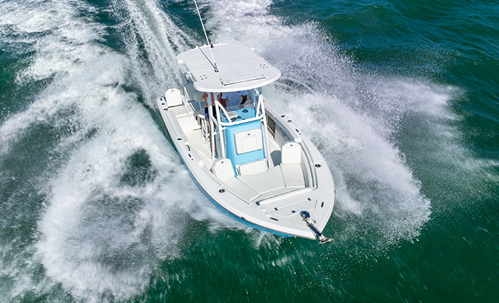 Aerial view of a white vessel speeding through open waters.