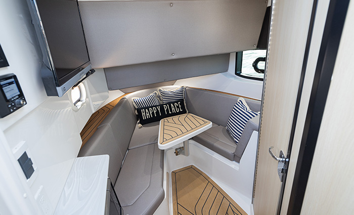 Gray and white seating booth with an embroidered "happy place" pillow.