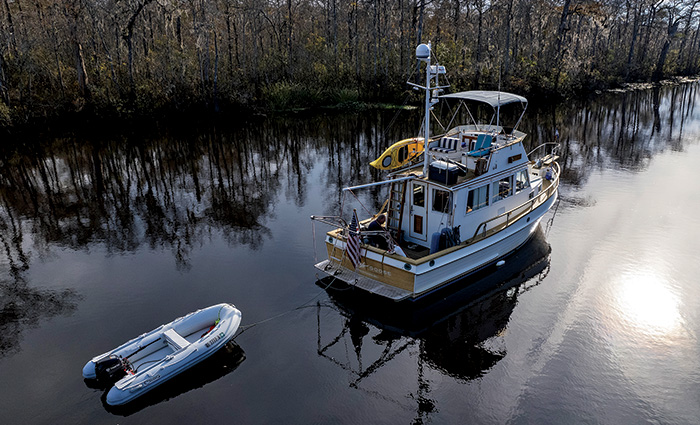 A white vessel with a yellow canoe pulling a small white motorized raft.