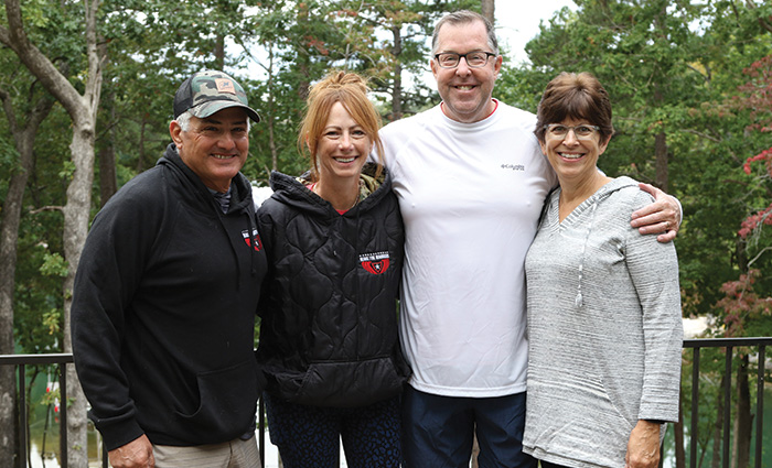 Two adult males and two adult females posing for a photo in front of the woods.