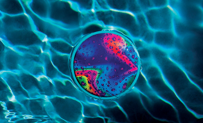 Multi-colored large unsinkable frisbee floating on clear water.
