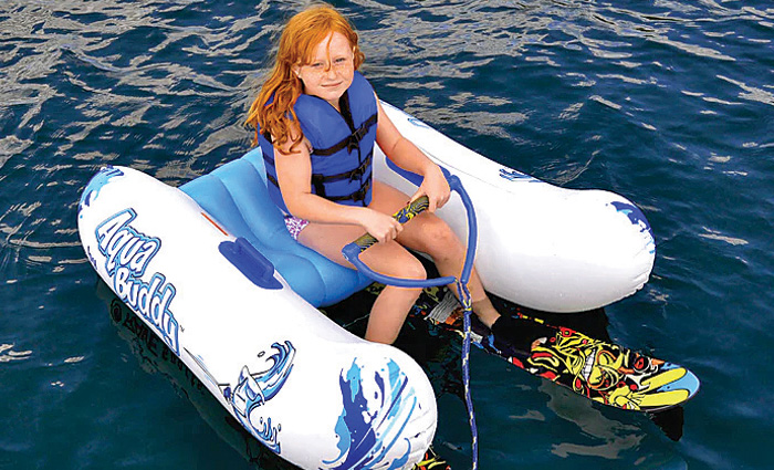 Red headed young female wearing a blue life jacket water skiing.