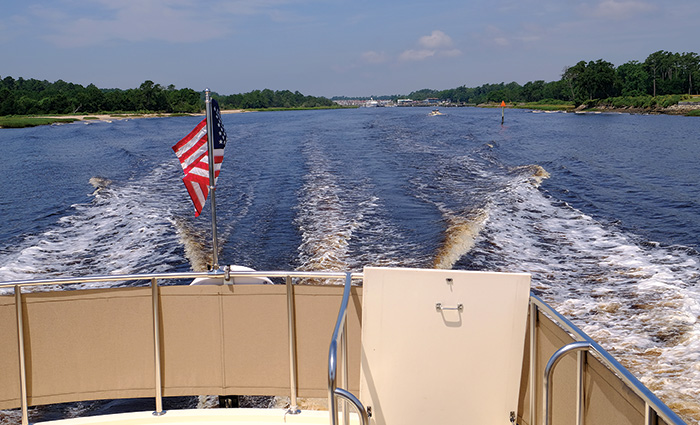 American flag on the back of a vessel while out on open waters on a sunny day.