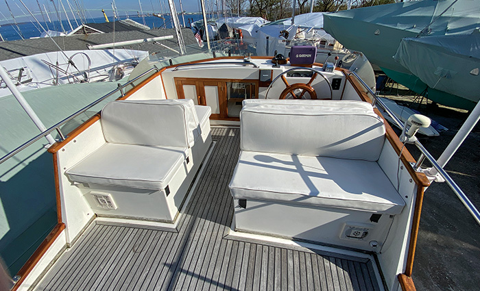 Dated white seats and worn deck of the flybridge of a vessel.