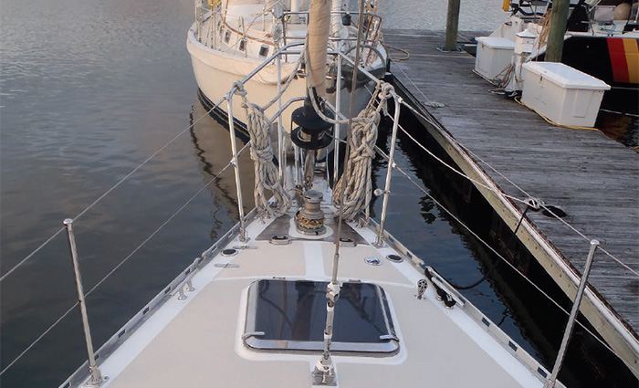 Ariel view of a large white vessel and lifelines on the water next to a wooden dock at sunset.