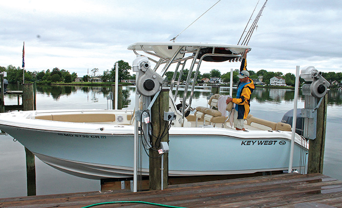 Side view of a man aboard a white vessel with tan seats on a lift during an overcast day.