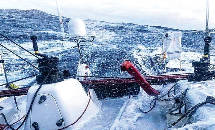 Rear view of a sailboat navigating rough waters.