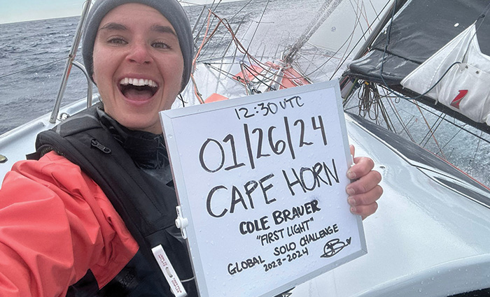 Smiling female aboard a white vessel holding a whiteboard with inspirational quotes.