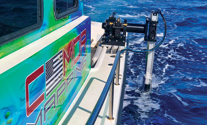 Up-close view of a tool attached to the side of a boat submerged in blue waters.