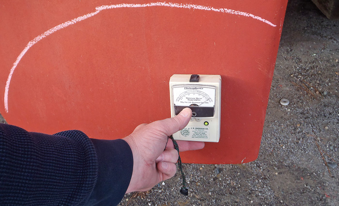 Hand holding a meter next to a red cored fiberglass fin.