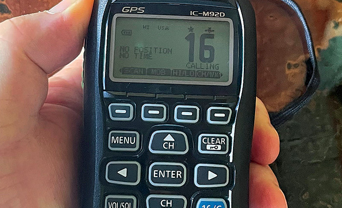 Hand holding a black VHF with display and buttons