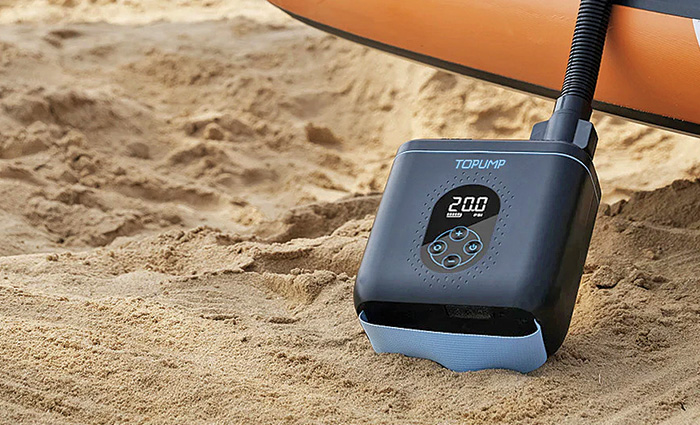 Small navy and blue pump next to an inflatable on the beach.