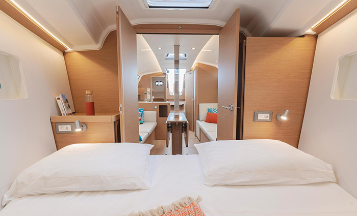 White bed with two white pillows in a room with a skylight.