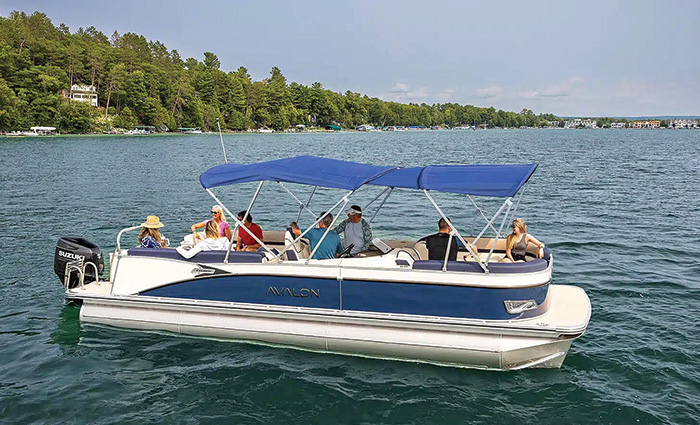 Group of adults aboard a blue and white pontoon boat on the water.