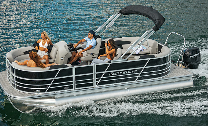 Adult male and three females aboard a black and silver pontoon boat on the water,