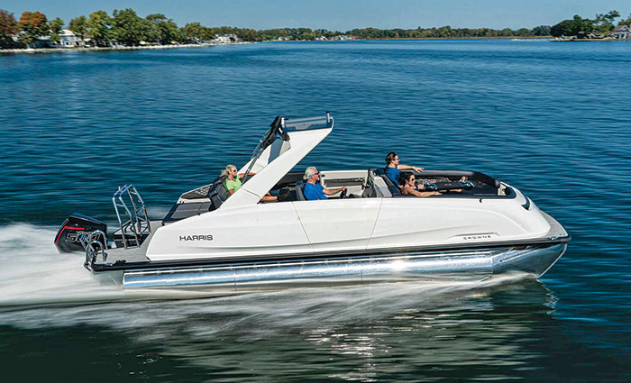 Four adults aboard a white pontoon boat speeding through open waters on a sunny day.