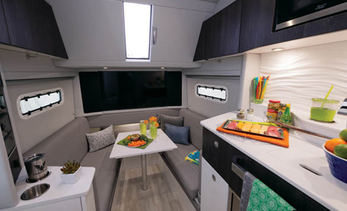 U-shaped gray sitting area, white table, sky light and counter inside a boat.