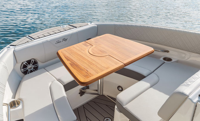 Seating area near the front of a vessel on the water featuring wrap around seating an a foldable wooden table.