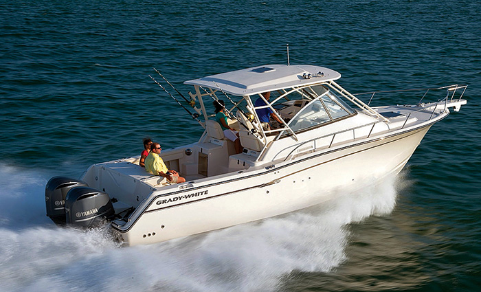 Four adults, two in front and two seated in the back, chopping through open waters in a white boat with two black engines  as sunshine reflects off the side.